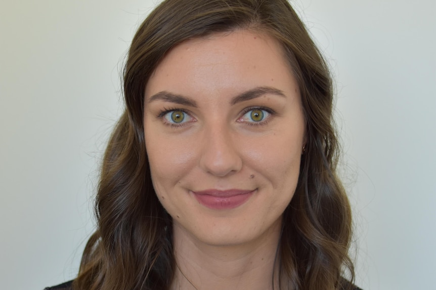 Woman with brown hair looks at camera in a headshot style photo