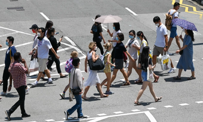People walk at a pedestrian crossing along the Orchard Road shopping district in Singapore on September 7, 2021. Photo by AFP