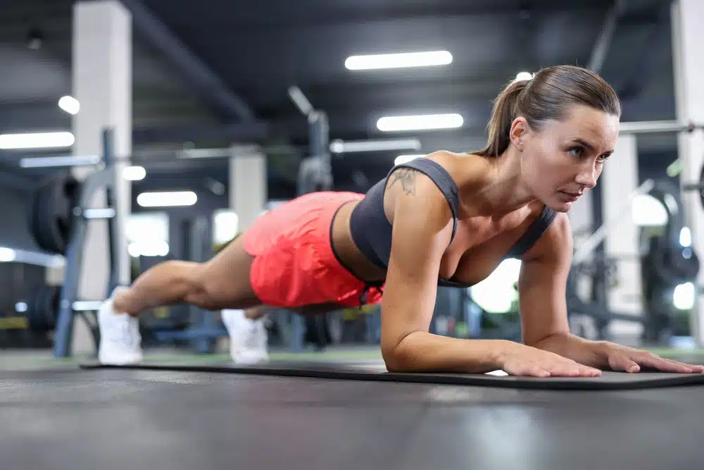 Athletic,woman,doing,plank,exercise,on,yoga,mat,in,gym