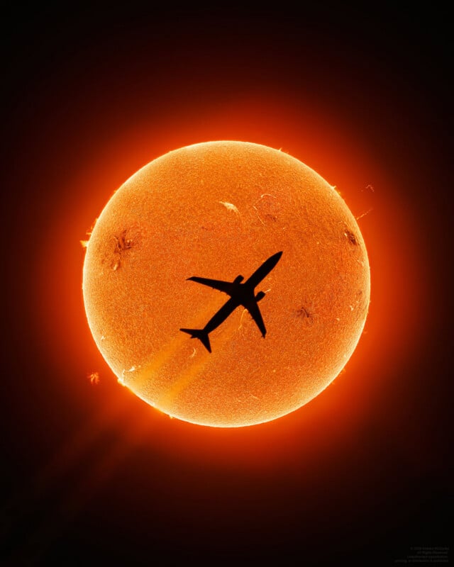 A silhouette of an airplane passes in front of the glowing, detailed surface of the Sun, with visible solar flares and sunspots in the bright orange and yellow solar disk.