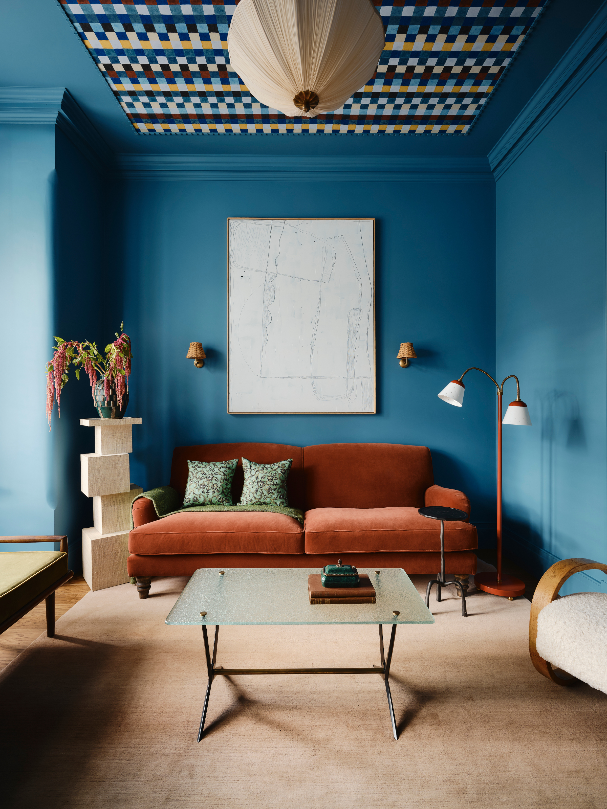 Blue snug with burnt orange sofa, geometric checkered pattern ceiling and beige carpet