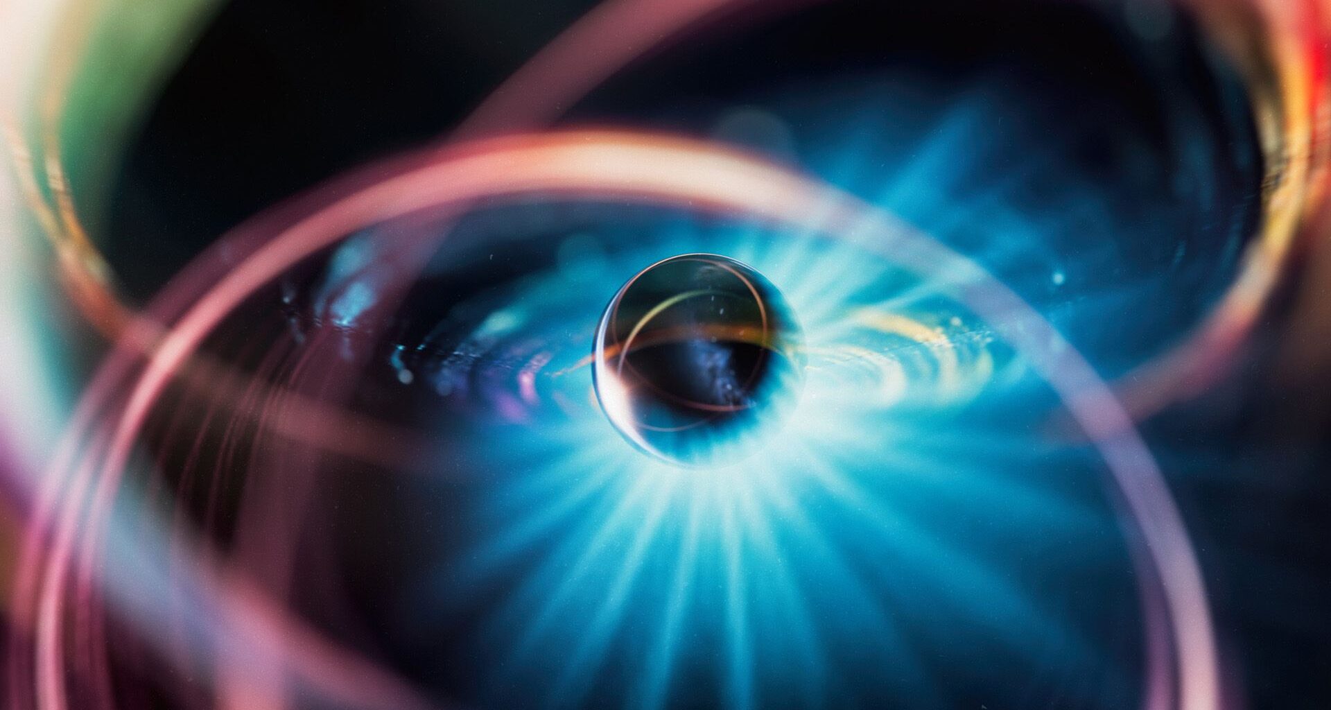 An illustration of a metal sphere surrounded by various colors and a glow of blue light.