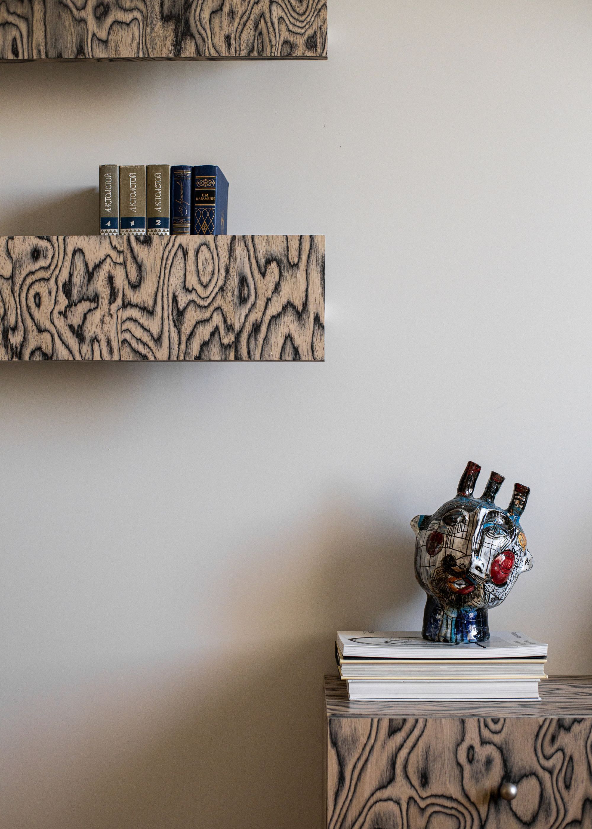 A living room with two floating shelve made in wood veneer, with books and decor pices kept atop