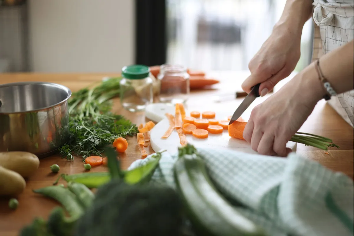 Someone cutting carrots at a messy kitchen counter