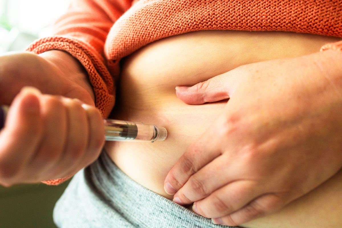 Someone injecting themselves in the abdomen with a semaglutide pen