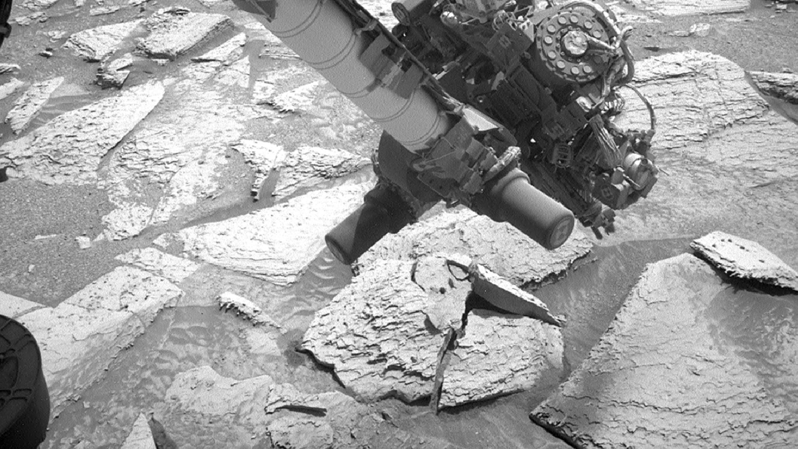 Photo of the robotic arm hovering over the remains of the Atacama rock after it fell off and fractured on the ground