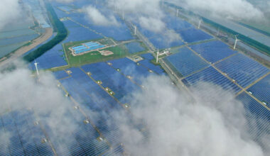 Aerial view of a solar power plant that's partly obscured by low-lying clouds.