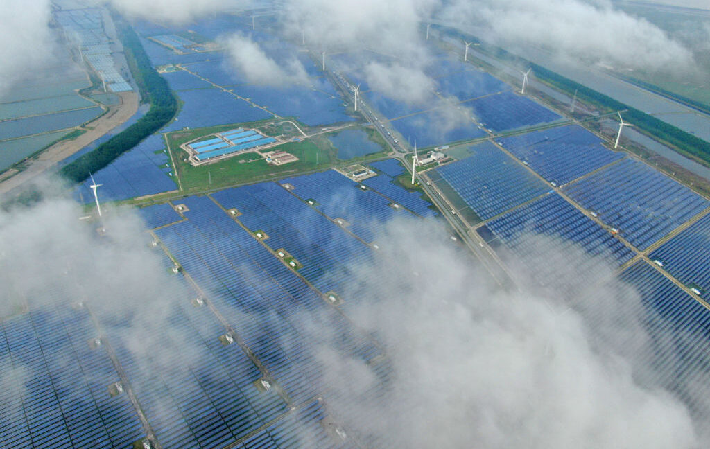 Aerial view of a solar power plant that's partly obscured by low-lying clouds.
