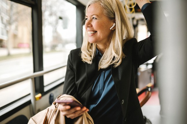 Happy businesswoman with smart phone travelling in bus