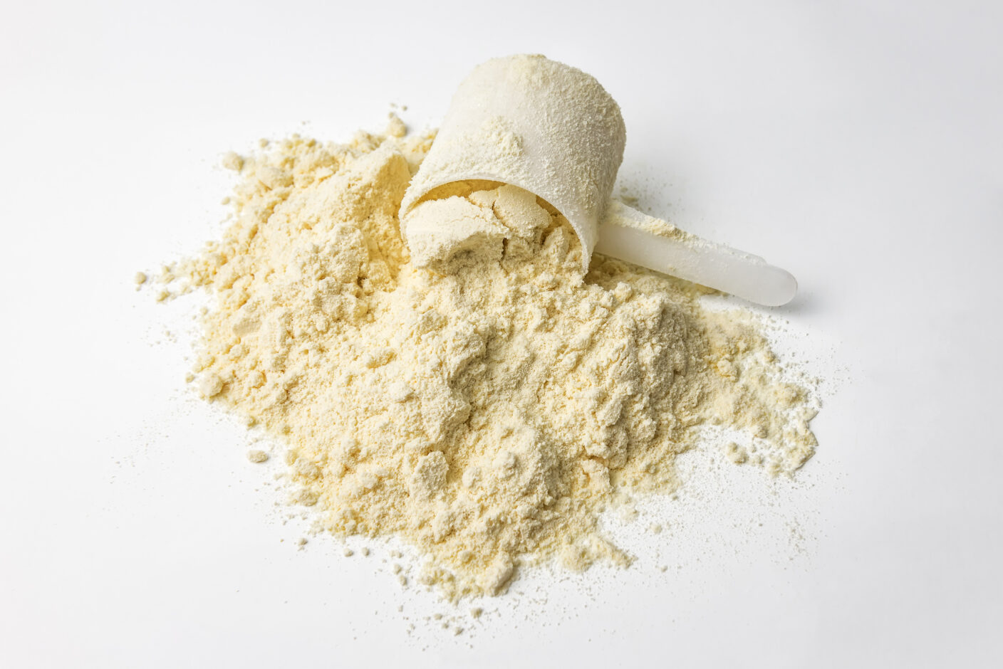 A photo of protein powder with a plastic scoop on a white background
