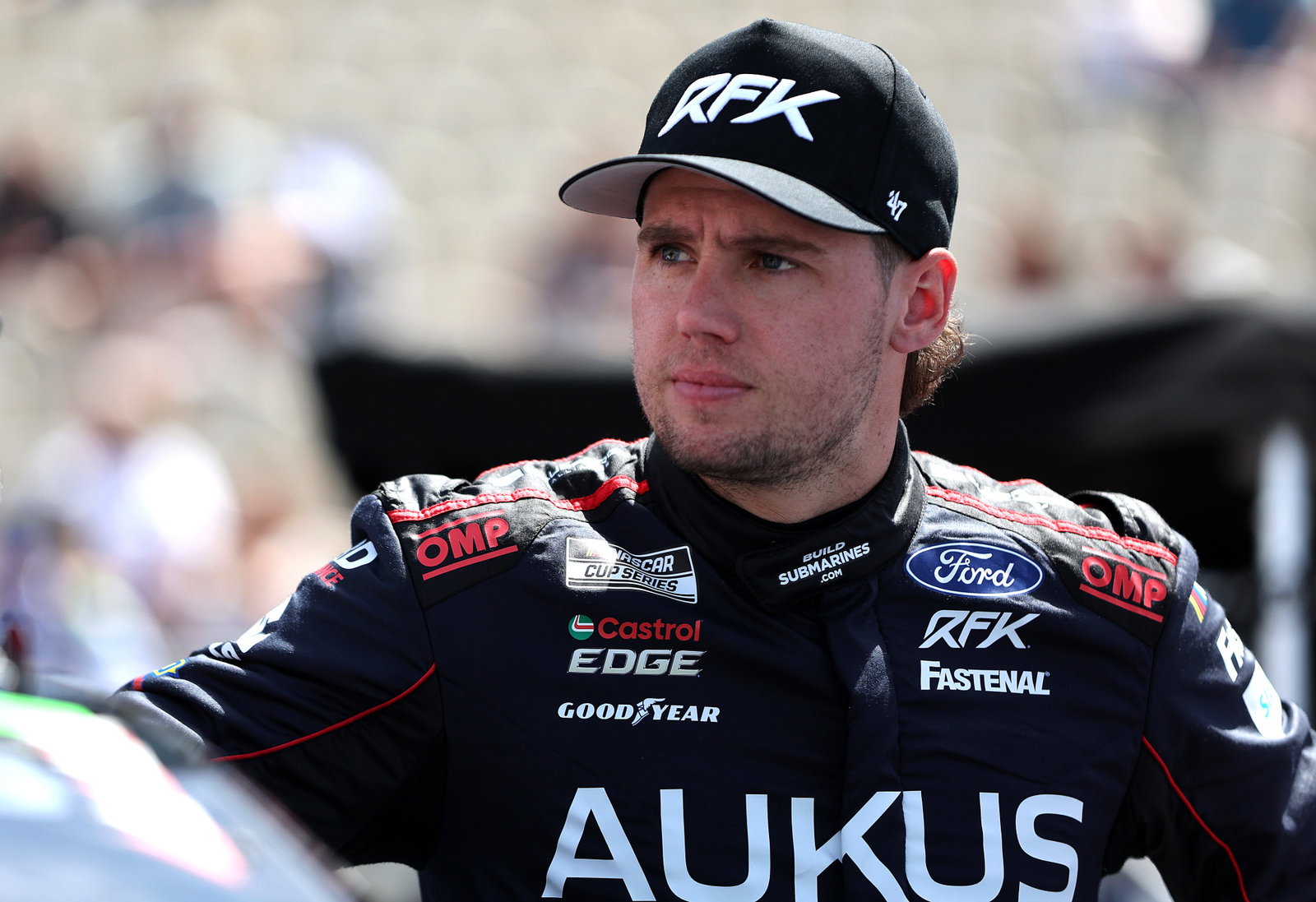 Cam Waters, driver of the #60 AUKUS/BuildSubmarines.com Ford, looks on during qualifying for the NASCAR Cup Series Toyota/Save Mart 350 at Sonoma Raceway in 2024.