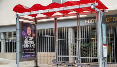Bus stop shelter with red canopy and ad for Artisan AI reading "Stop Hiring Humans" and "For Work They Hate" on city sidewalk, San Francisco, California, September 30, 2025. (Photo by Smith Collection/Gado/Getty Images)