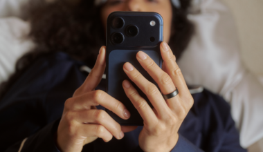 Person looking at phone screen lying in bed wearing Oura Ring 5
