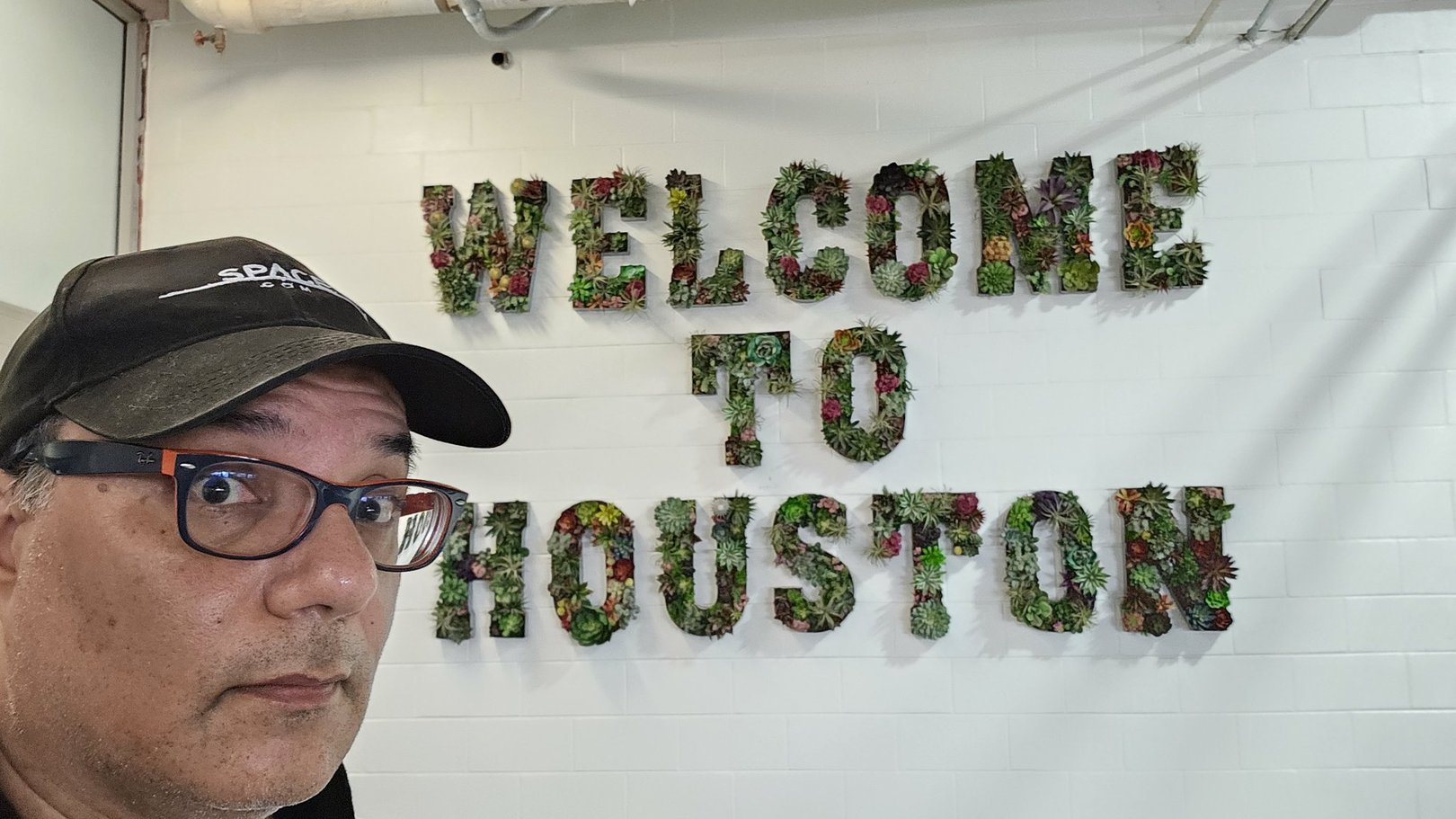 A man looks at the camera while standing in front of a sign that reads 