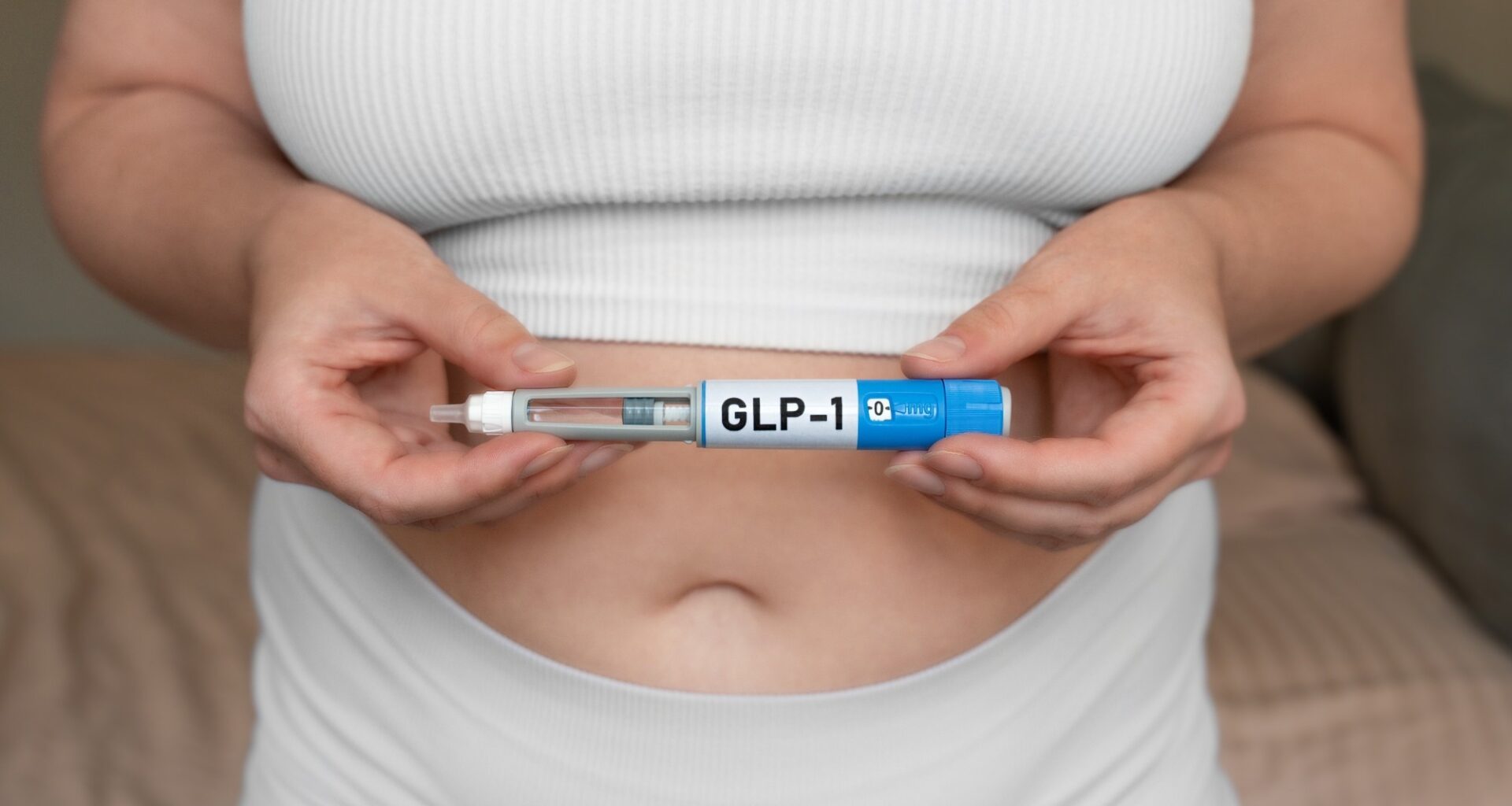 Close-up of woman holding GLP-1 injection pen near stomach, modern medical treatment for weight loss and blood sugar control