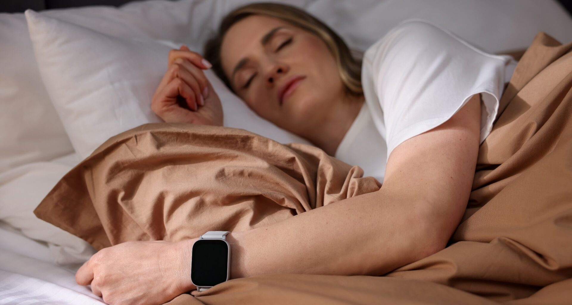 Woman with sleep tracker sleeping on bed at home