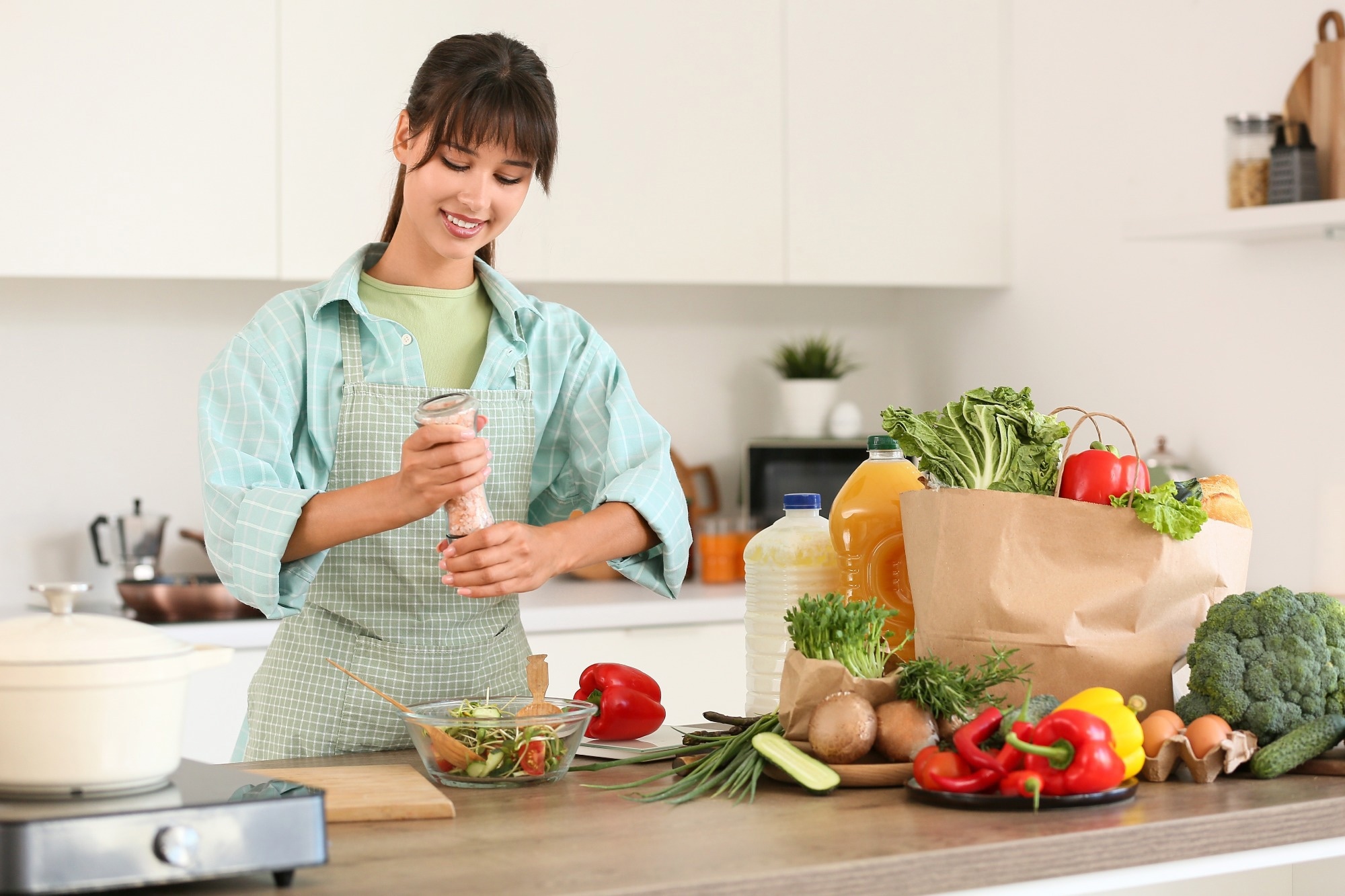 Young woman salting vegetable salad in kitchen