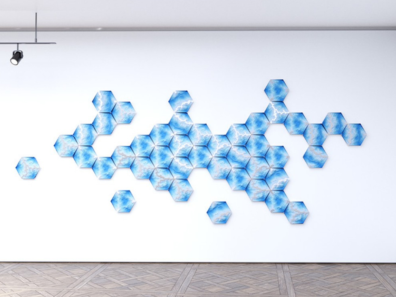Blue hexagon wall mural forming a geometric honeycomb pattern on a white gallery wall and wooden floor, left-aligned with a few isolated hexagons offshoots.