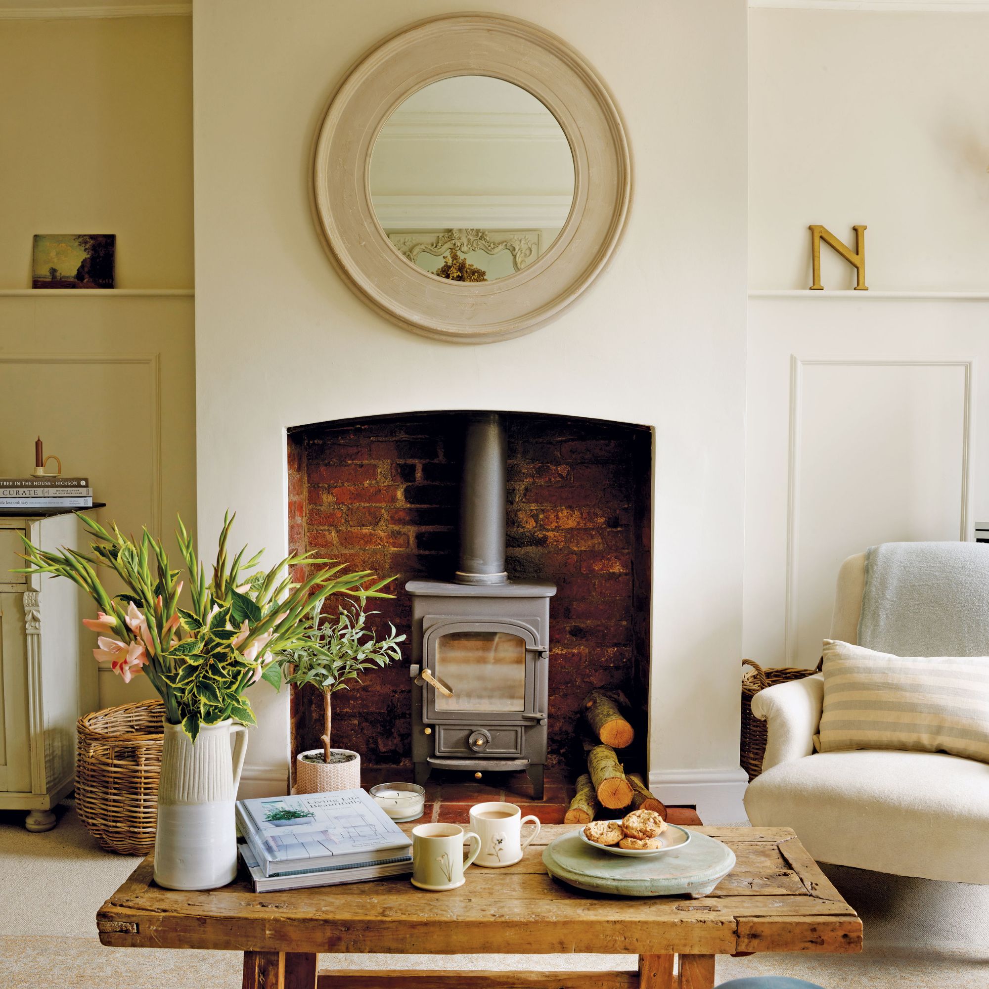 Living room in cottage with wood burner, round mirror and wooden coffee table