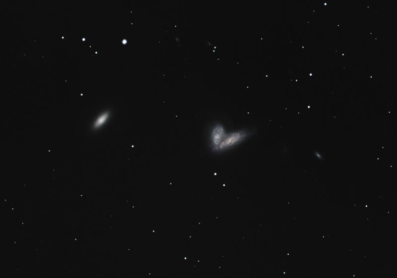 A trio of small, yellowish patches of nebulosity, overlaid with a sparse background of stars.