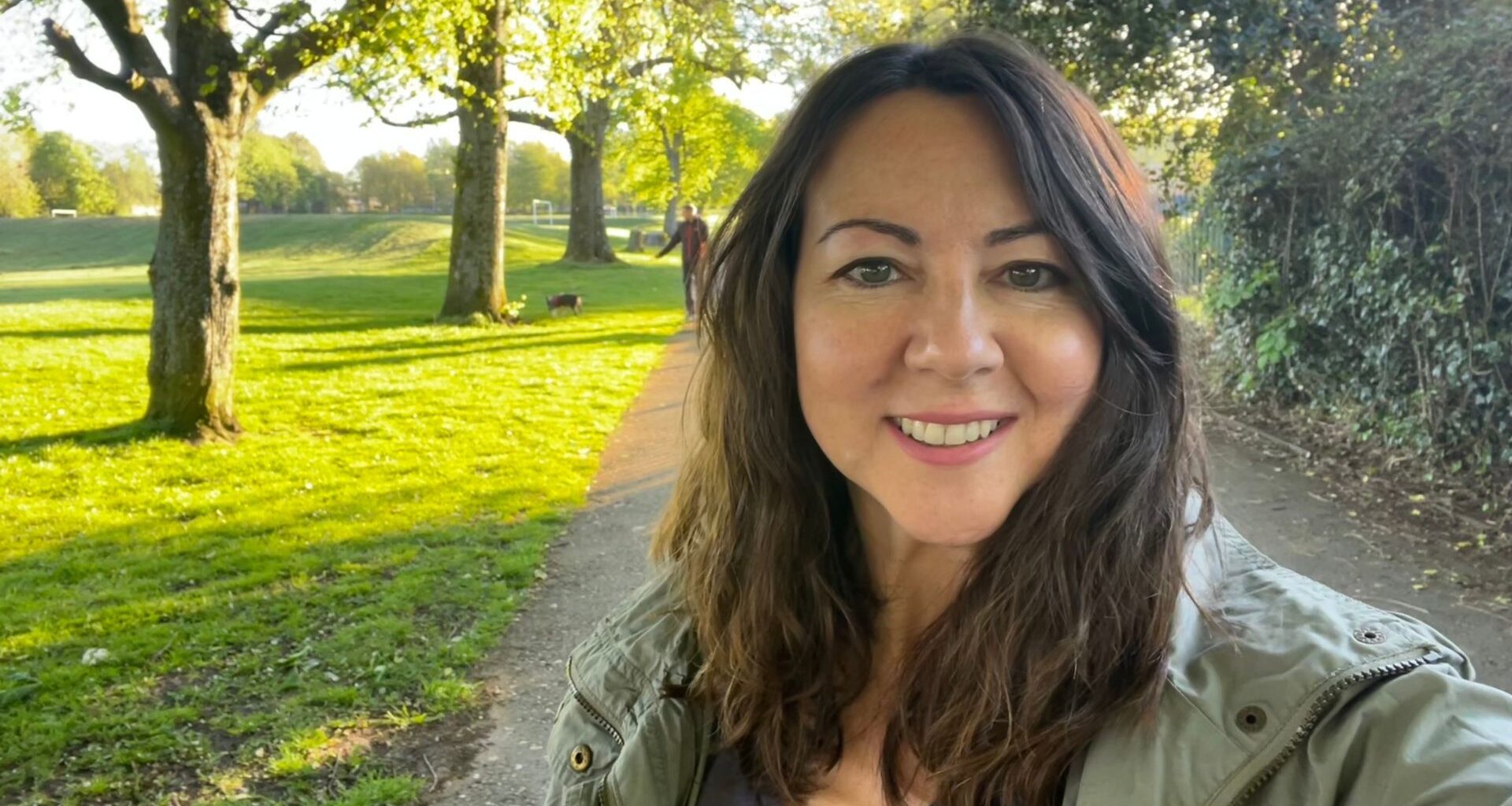 Susan Griffin doing 10-minute walking workout through sunny park, smiling