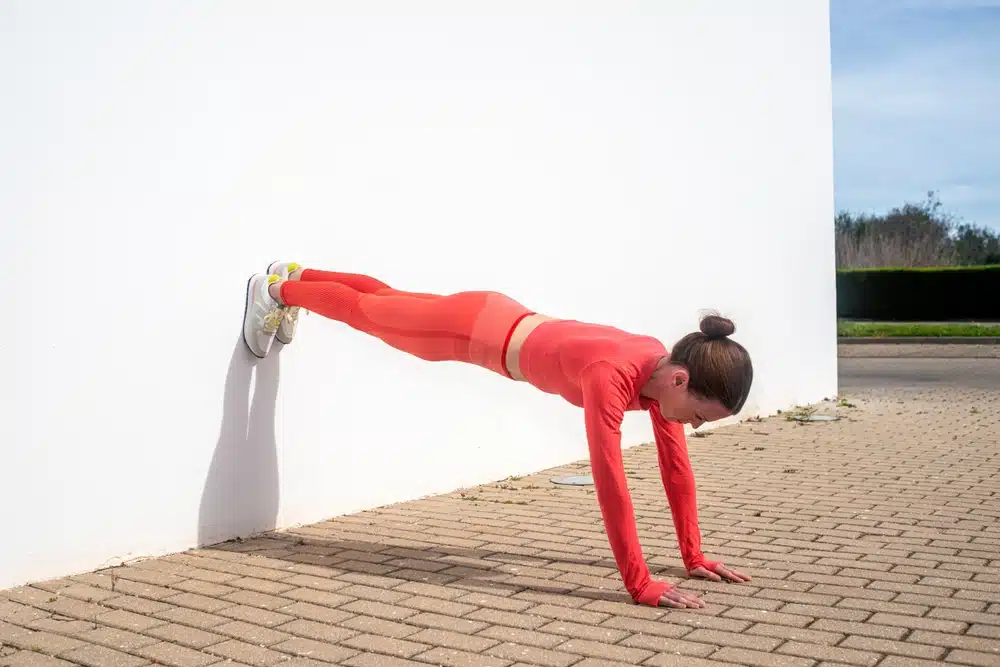 Sporty,woman,doing,a,plank,pose,exercise,against,a,wall