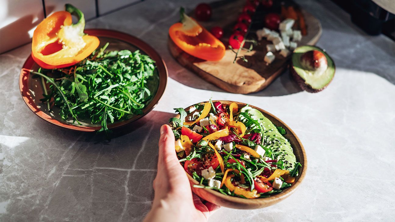 Female hands holding salad bowl with veggies