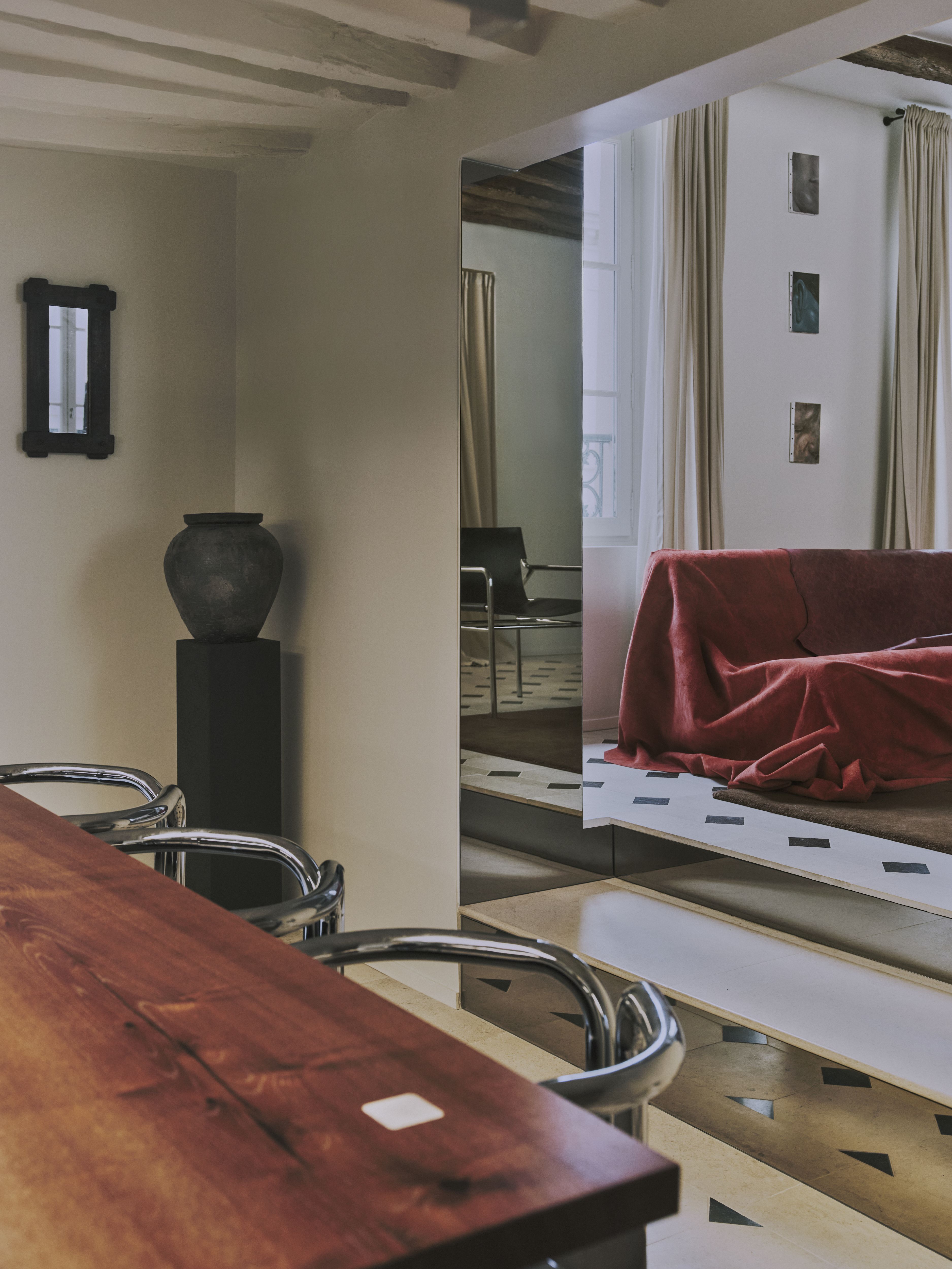 A sleekly designed apartment with tiled white and black checkered floors, chrome surfaces, brick walls, and occasional pops of red, ming green, and butter across linearly cut furniture.