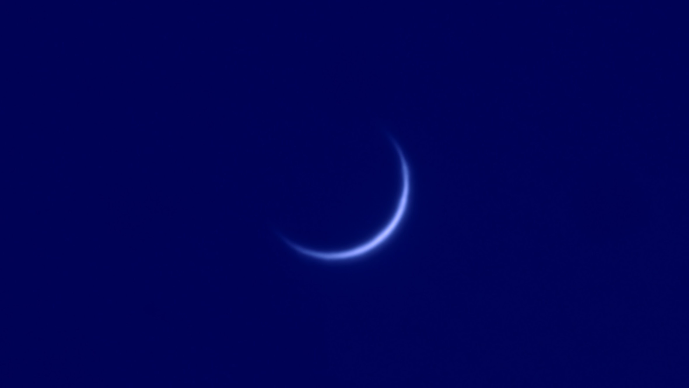 thin crescent venus against a dark blue sky.
