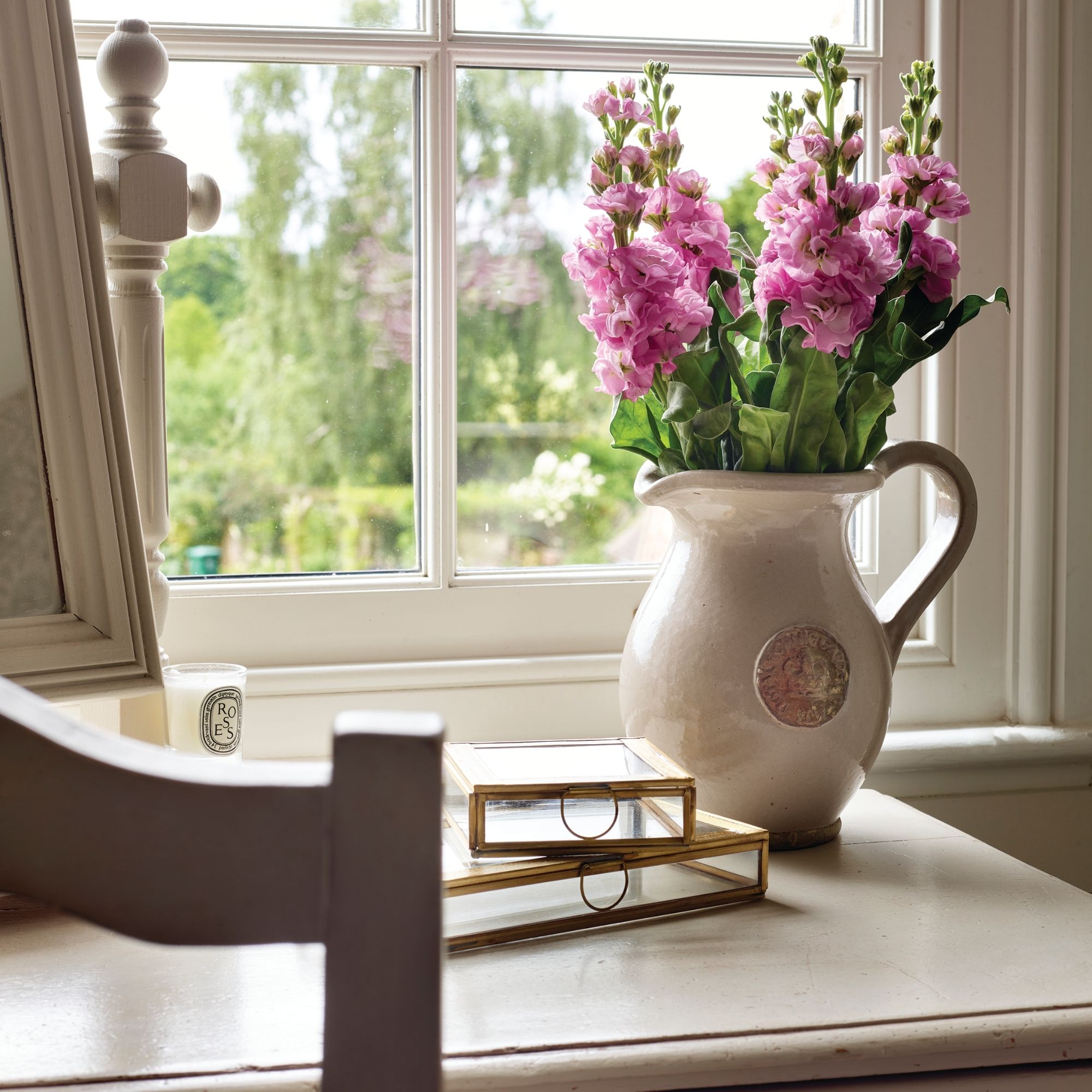 Dressing table in cottage home with jug of pink flowers