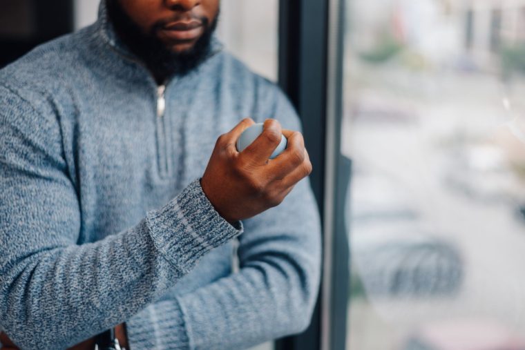 Office worker squeezing stress ball, managing workplace pressure and anxiety during workday