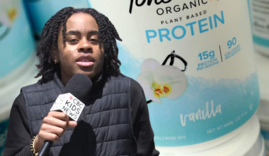 A kid stands, speaking into a handheld microphone, and the background has an image of protein powder.