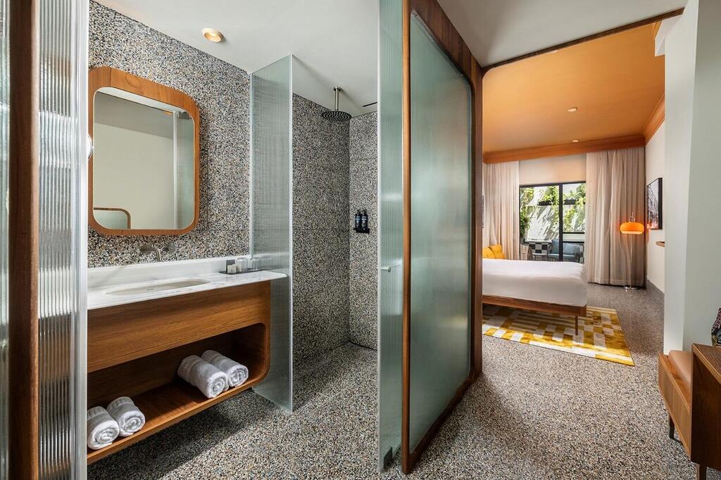 A bathroom clad in black-and-white terrazzo, with glass and teak elements (Photo: Suzie Levinson and Idan Goor) מלון 1935 ברנר 5 תל אביב