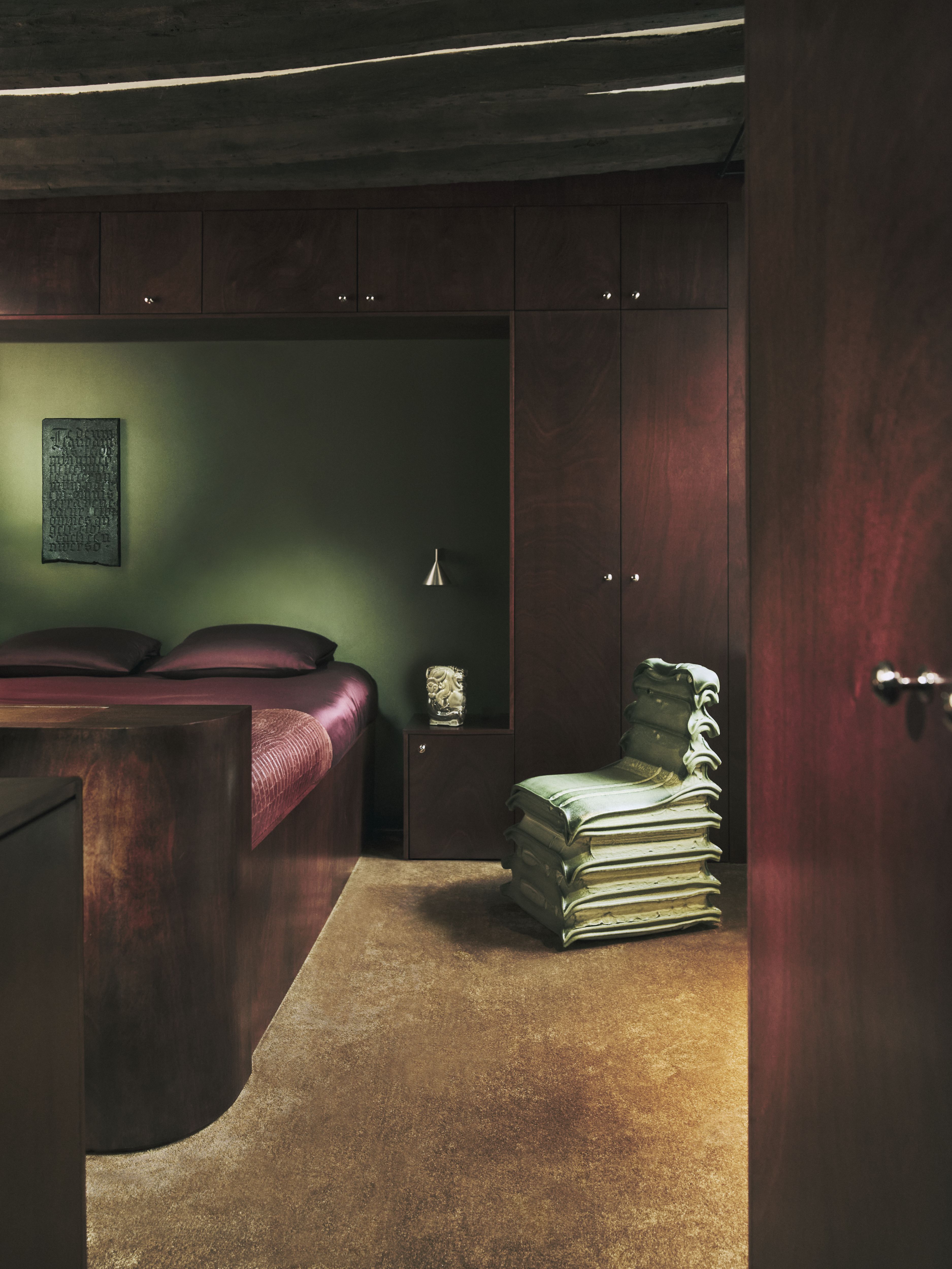 A sleekly designed apartment with tiled white and black checkered floors, chrome surfaces, brick walls, and occasional pops of red, ming green, and butter across linearly cut furniture.