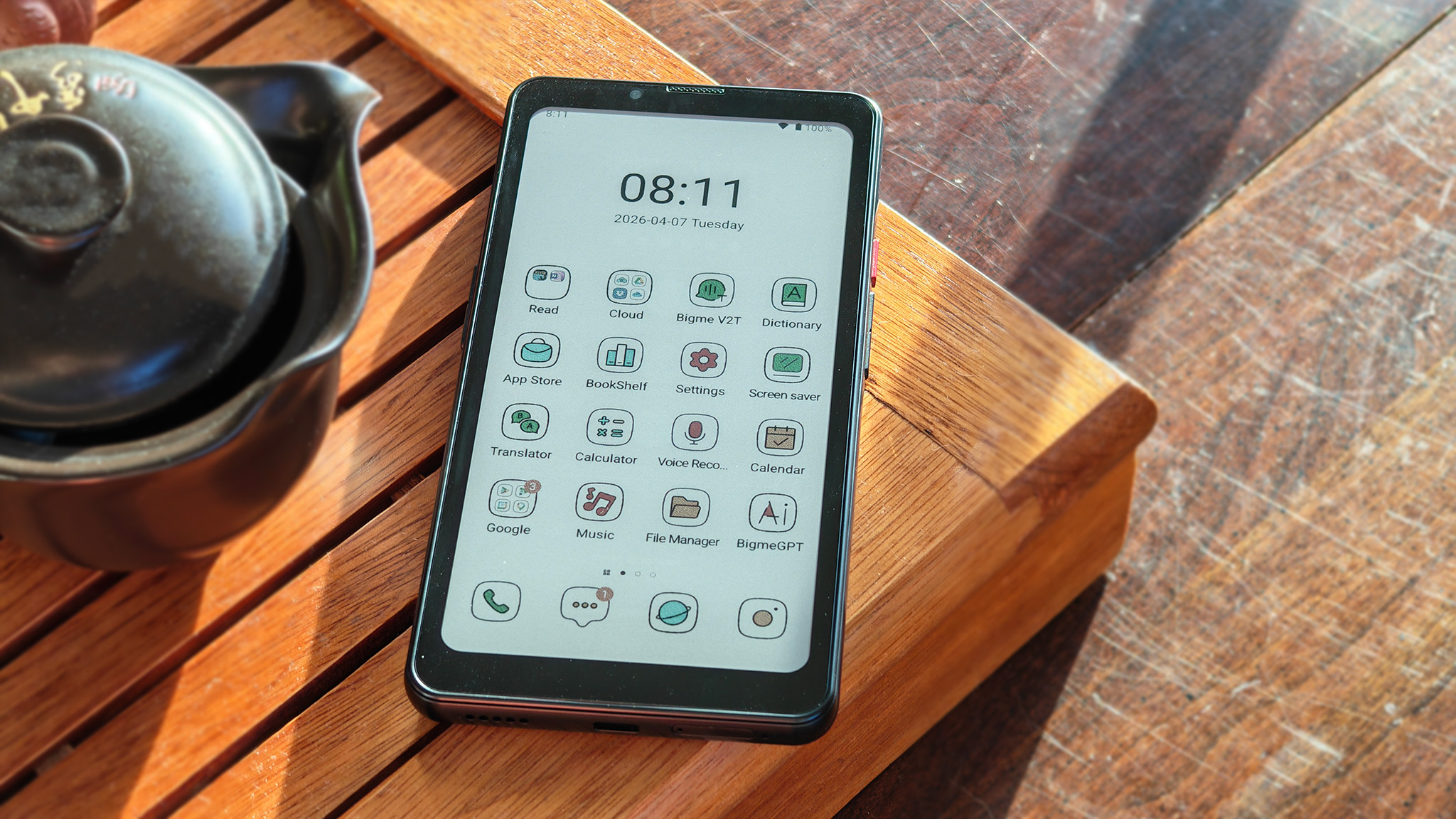 A Bigme HiBreak Pro Color on a tea tray with its home screen illuminated by sunlight