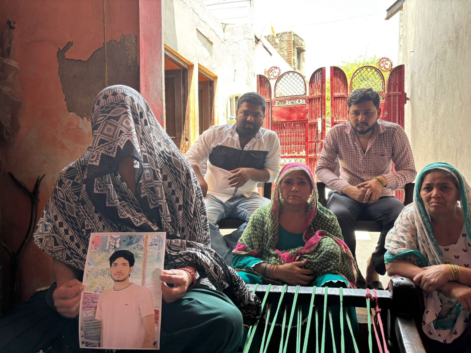 Pawan's family at their residence in Nuh. His mother sits holding his picture | Samridhi Tewari | ThePrint