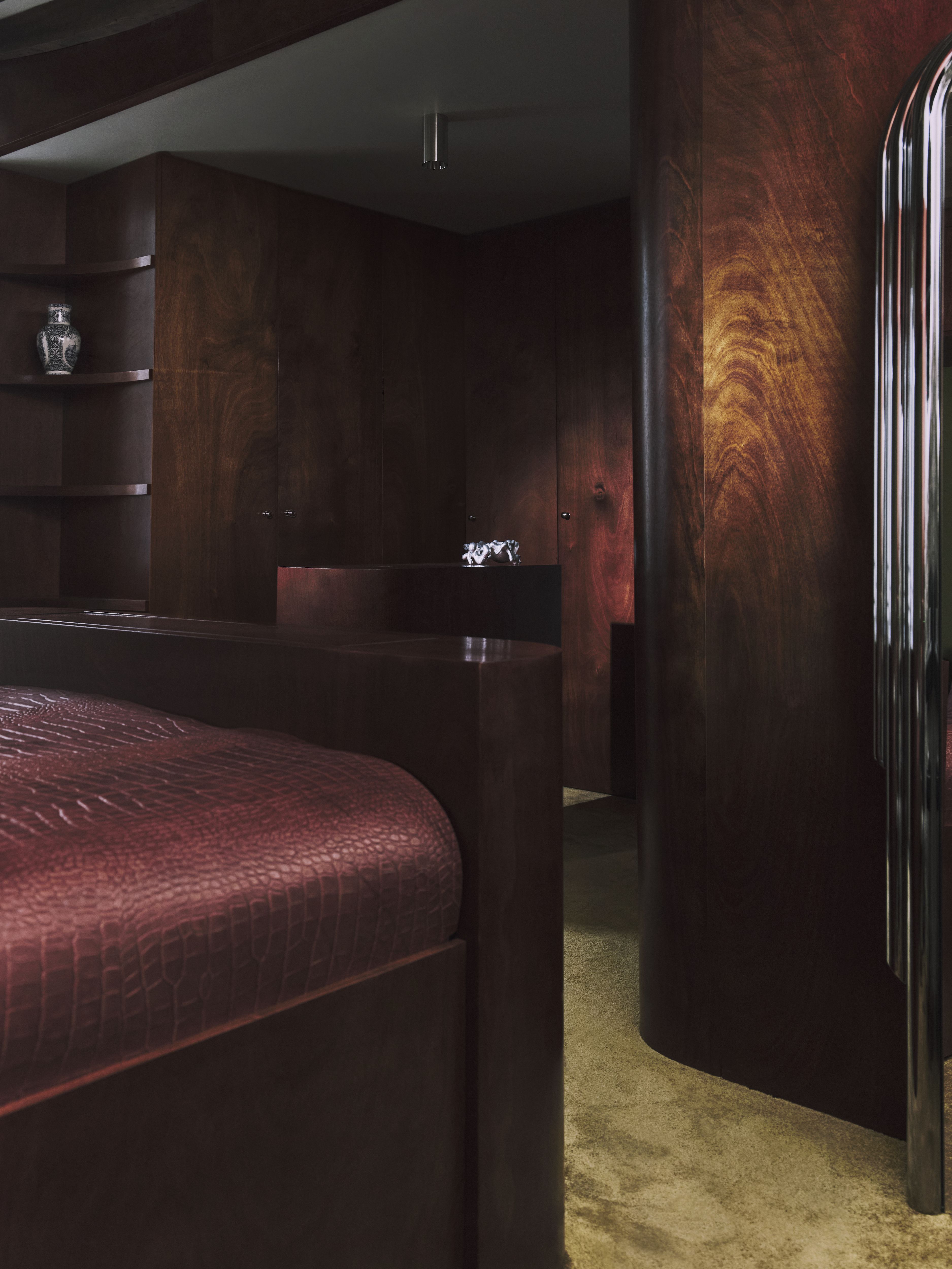 A sleekly designed apartment with tiled white and black checkered floors, chrome surfaces, brick walls, and occasional pops of red, ming green, and butter across linearly cut furniture.