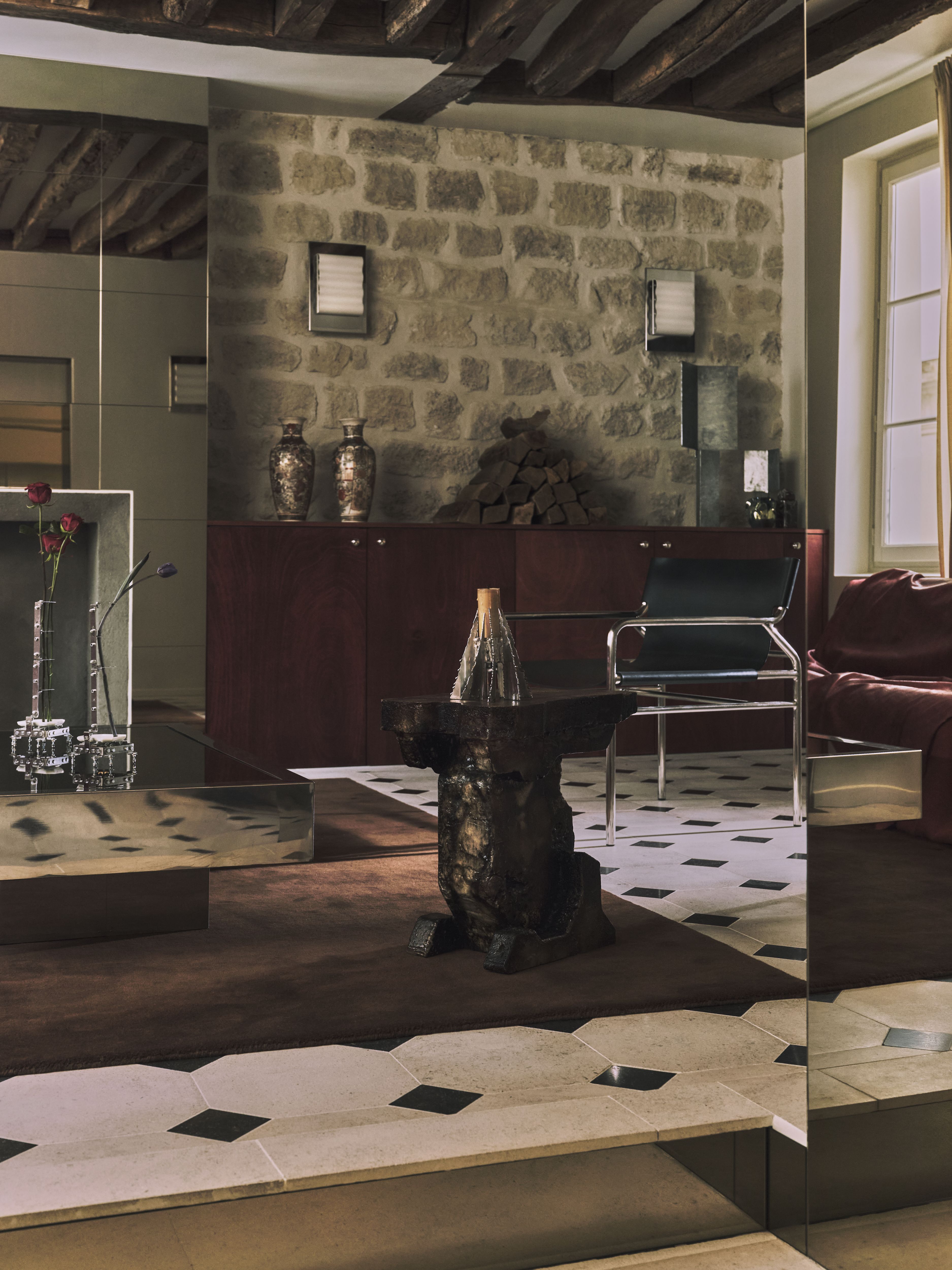 A sleekly designed apartment with tiled white and black checkered floors, chrome surfaces, brick walls, and occasional pops of red, ming green, and butter across linearly cut furniture.