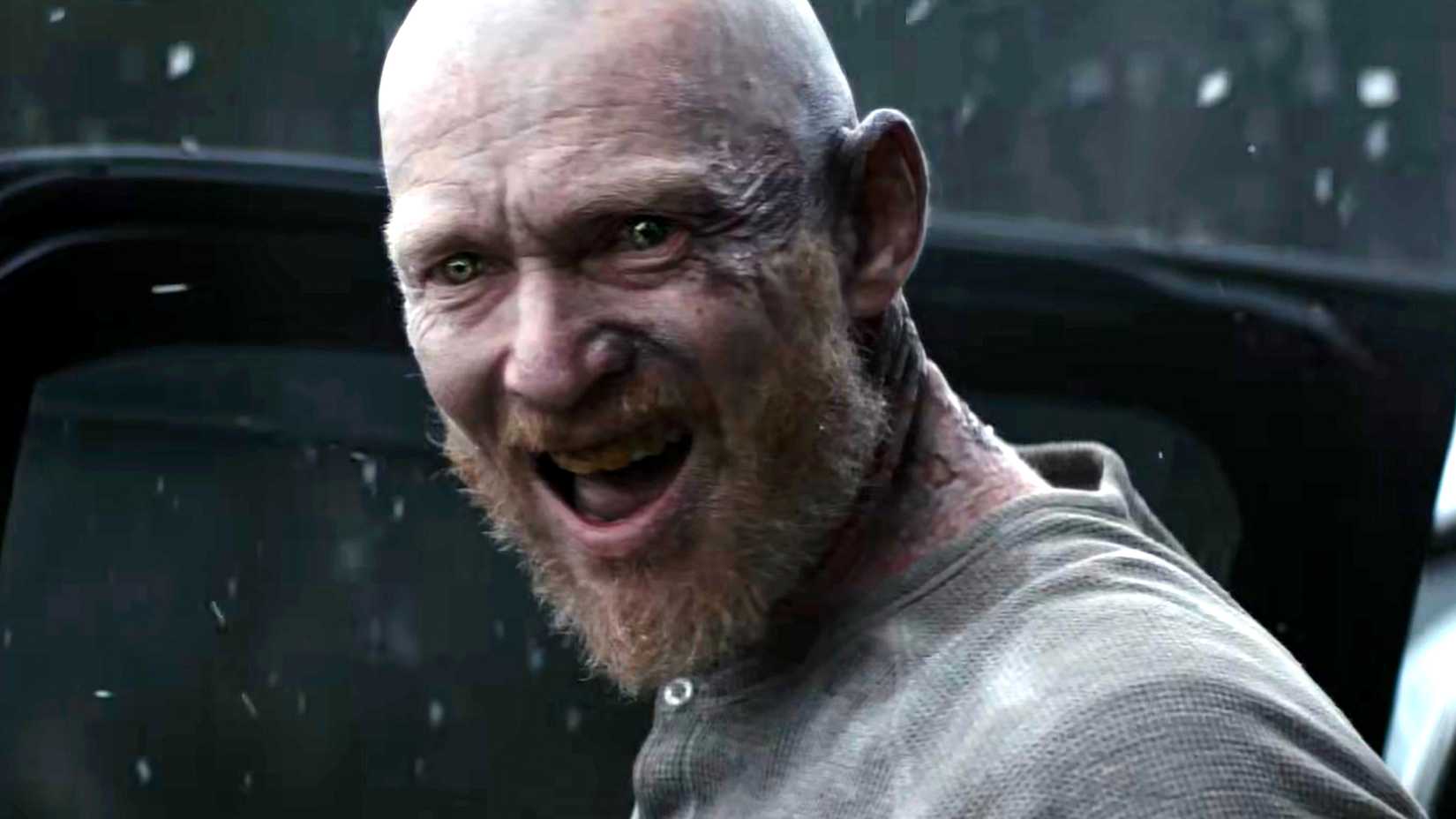 A Deadite smiling creepily toward the camera in Evil Dead Burn
