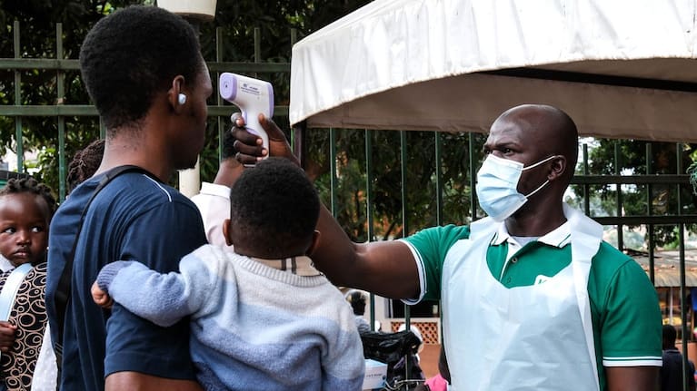 A health official uses a thermometer to screen people in front of Kibuli Muslim Hospital in Kampala, Uganda.