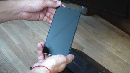 A man holding an Android phone trying to power it on