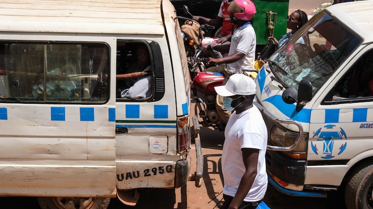 A man wearing a protective mask walks along a busy street in Kampala, Uganda.