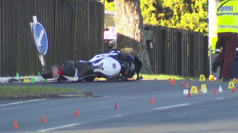 A motorcycle lays on the ground surrounded by police following a crash with a car in Auckland's Howick.