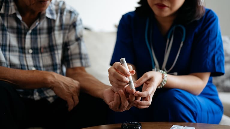 A nurse conducts a blood glucose test on patient.