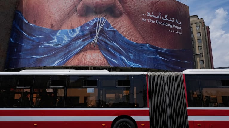 A public bus drives past a billboard with graphic showing Strait of Hormuz and sewn lips of US President Donald Trump in a square in downtown Tehran, Iran, Saturday, May 2, 2026.