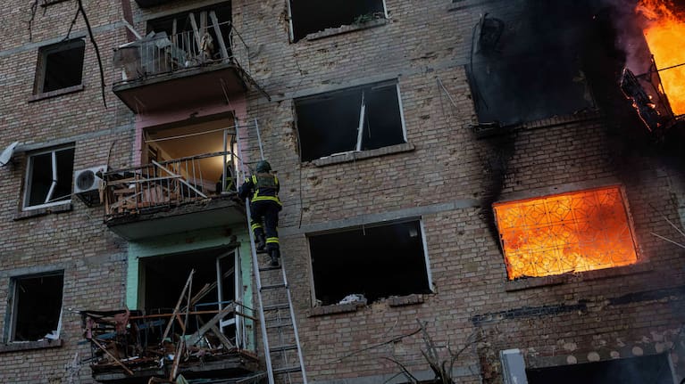 A rescue worker climbs on a ladder to help evacuate people from a residential building being destroyed after a Russian strike on Kyiv, Ukraine.