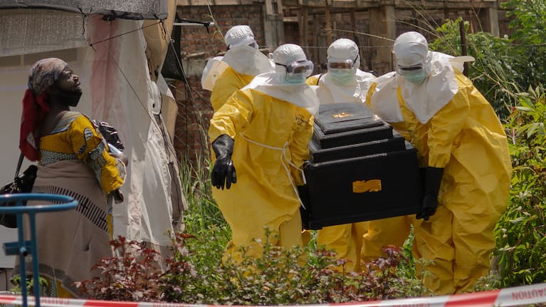 A woman cries as Red Cross workers carry the coffin of a person who died of Ebola from a health center in Rwampara, Congo.