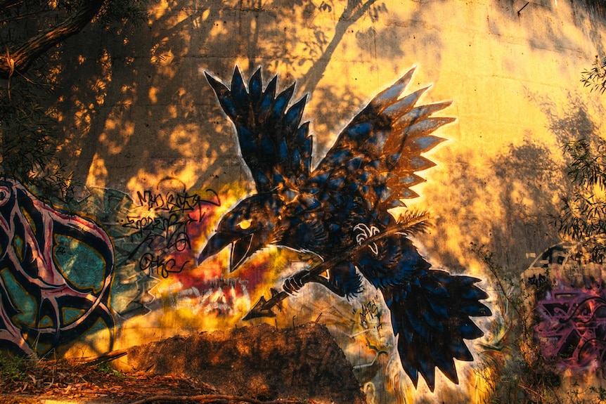 A crow graffitied on the inside of a storage tank, dappled with sunlight.