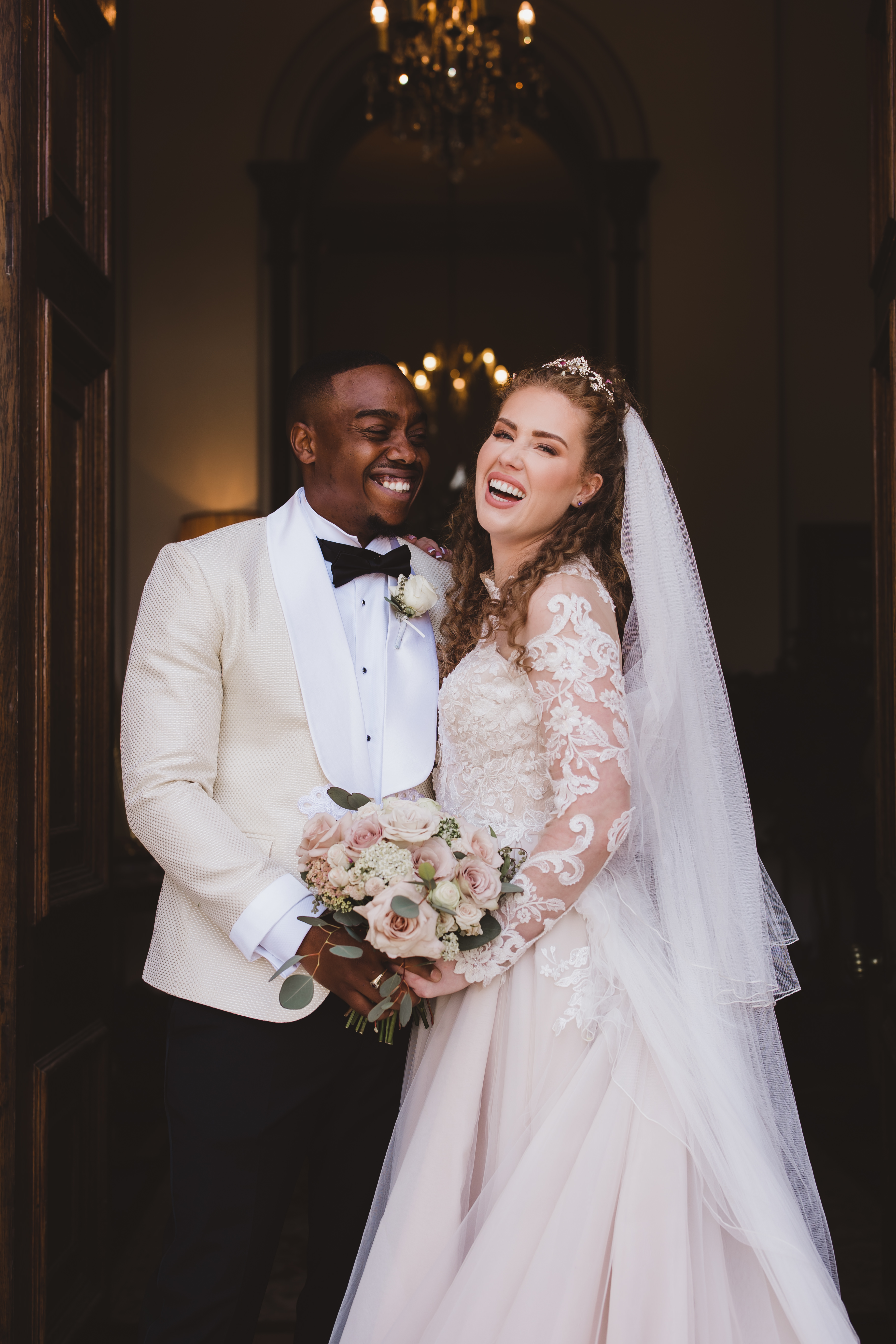 A wedding couple laughs while standing in a wooden doorway