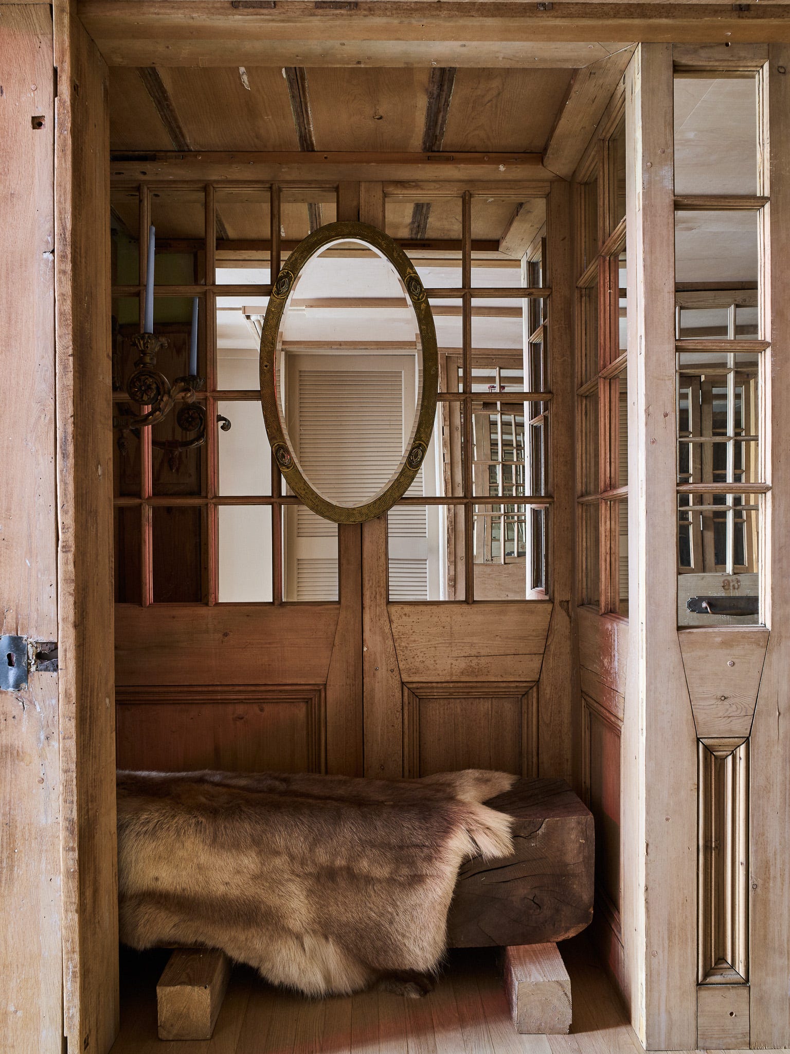 Wooden entryway with a bench, mirror, and candle holder
